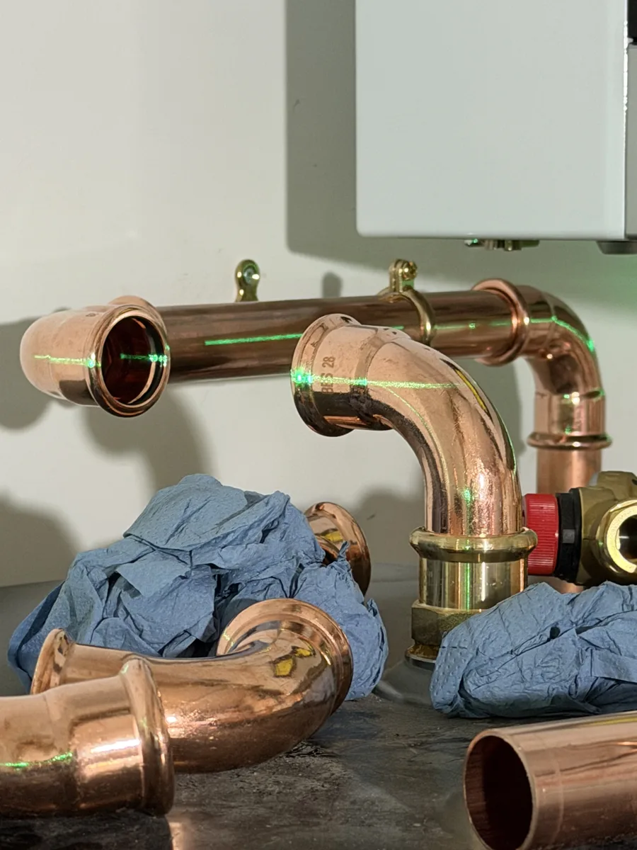 Copper press fittings aligned with a laser level during a heating installation