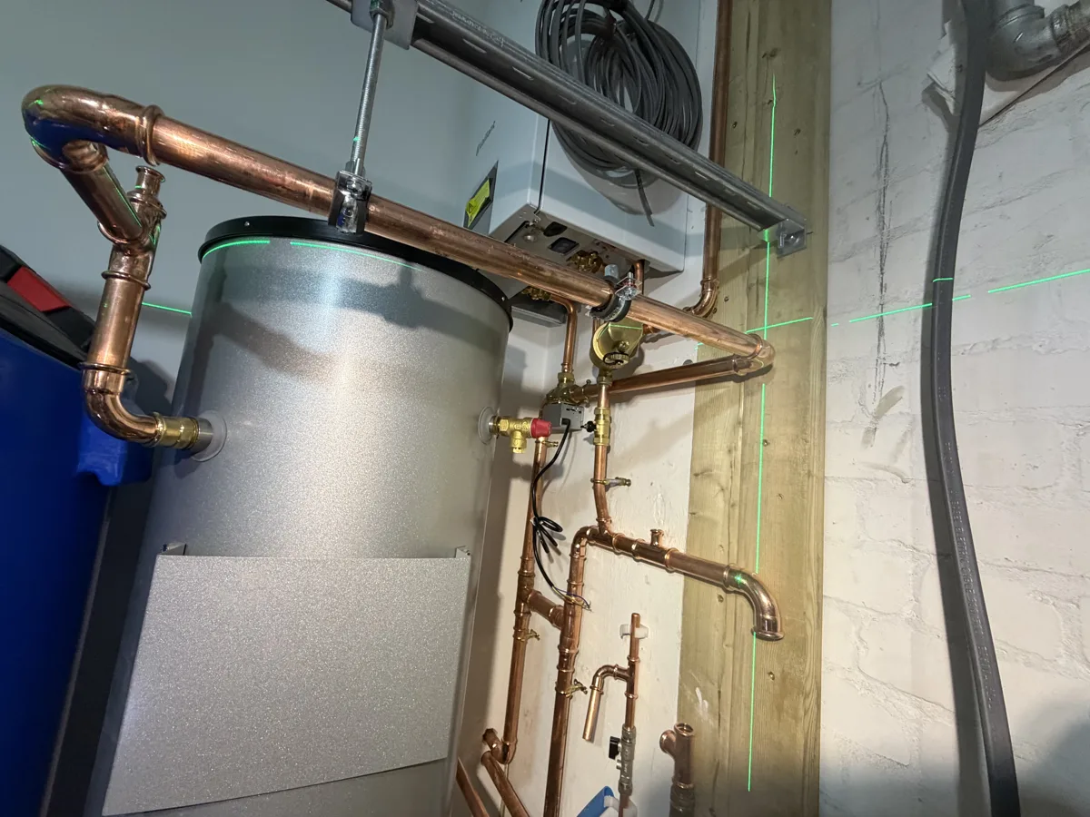 Laser-levelled copper pipework for a hot water cylinder installation in Chelsea